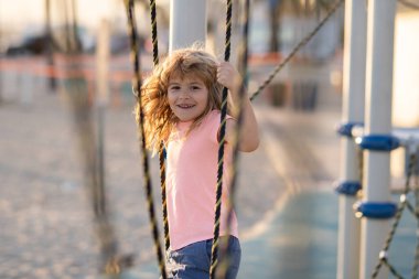 Çocuklar güneşli yaz gününde dışarıda oynar ve tırmanırlar. Çocuk çocuk çocuk parkında oynuyor. Çocuk parkında aktif küçük çocuk.