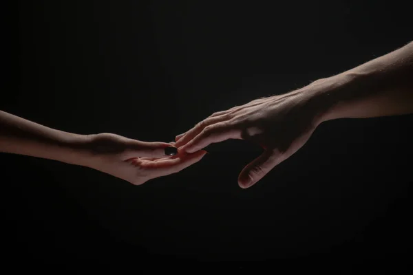 Two hands stretch each other, black background. Couple in love holding hads, close up. Helping hand, support, friendship. — 스톡 사진
