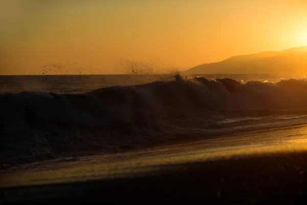 Céu dourado e água do oceano. Fundo das ondas do mar. Nascer do sol sobre o mar tropical. Pôr do sol colorido com salpicos de onda na praia. — Fotografia de Stock