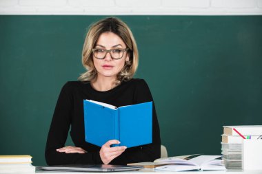 Teacher in classroom at university or college. Female student on board with book. Lesson seminar skills. Young woman study in high school. Study concept.