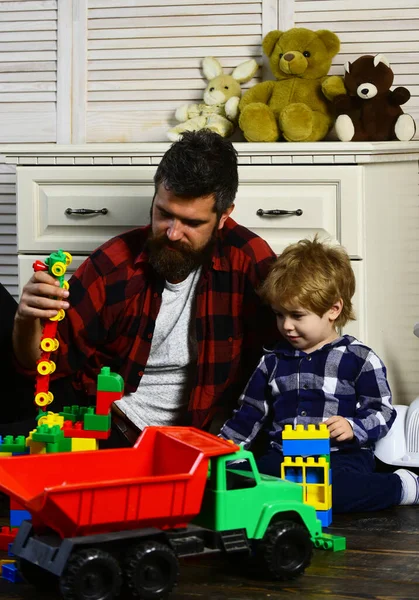 Ребенок и папа играют в игрушки Лего. Отец и сын создают игрушки из кирпича. Папа и ребенок из пластиковых блоков. — стоковое фото