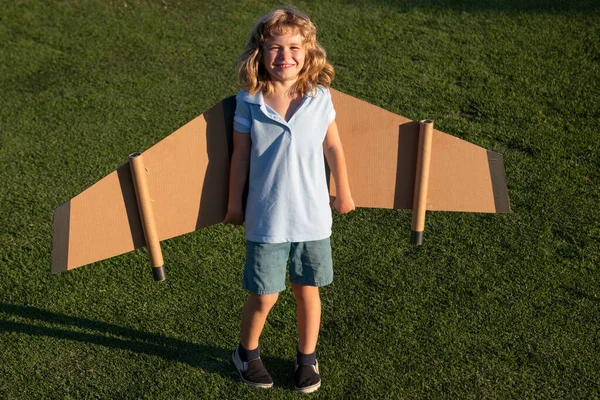 Söt drömmarpojke som leker med ett flygplan av papp. Barndom. Fantasi, fantasi. — Stockfoto