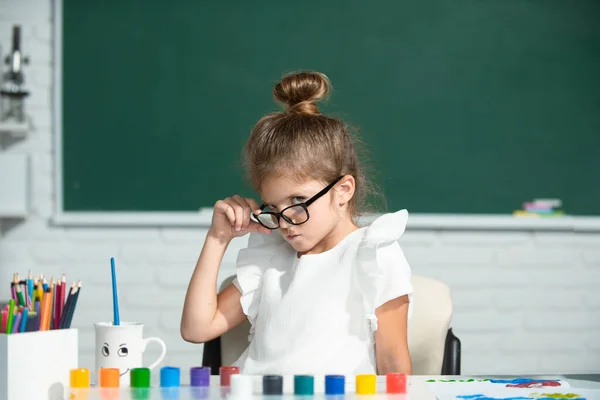 Cute little preschooler child girl drawing at school. Child girl painting on elementary school. Cute school girl face. — Fotografia de Stock