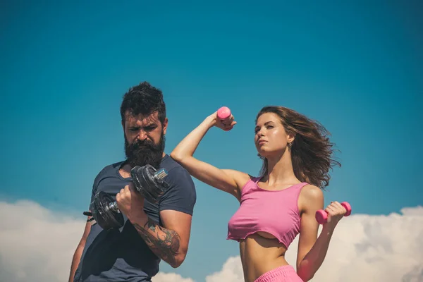 Couple sportif avec haltère à l'extérieur. Couple travaillant avec des haltères. Club de fitness extérieur sur la nature. Fitness modèles sexy pompage bras avec haltère. — Photo