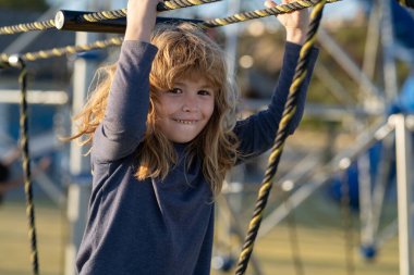 Çocuk ağa tırmanıyor. Çocuk dışarıda oyun oynuyordu. Çocuklar okulda ya da anaokulunda oynarlar. Aktif çocuk renkli kayıyor ve sallanıyor. Çocuklar için sağlıklı yaz etkinliği.