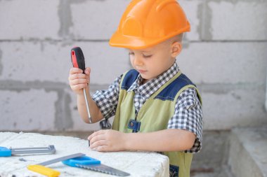 Tornavida tutan küçük çocuk. Çocuk tornavidayla cıvata çeviriyor. Tamir aletli küçük bir tamirci. İnşaat işçisi olarak sevimli bir çocuk. Çocuklar çekiç pense ve tornavidayla oynar..