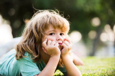 Summer kids dream outdoor portrait. Happy child enjoying on grass field and dreaming. Kids on green grass background.
