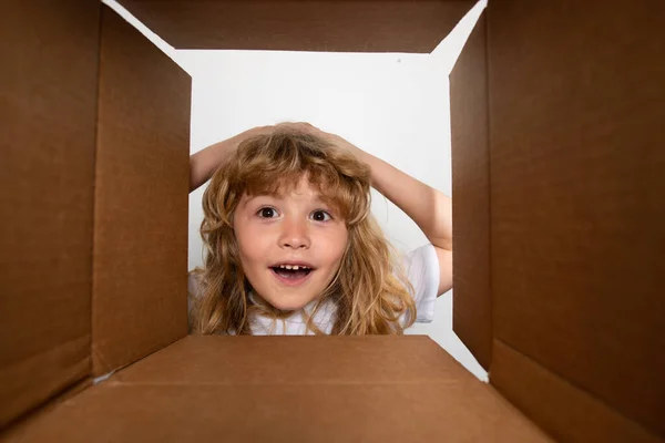 Funny excited child unpacking and opening the carton box looking inside. The little kids unboxing gift inside view. Open box and delivery parcel for children. — Photo