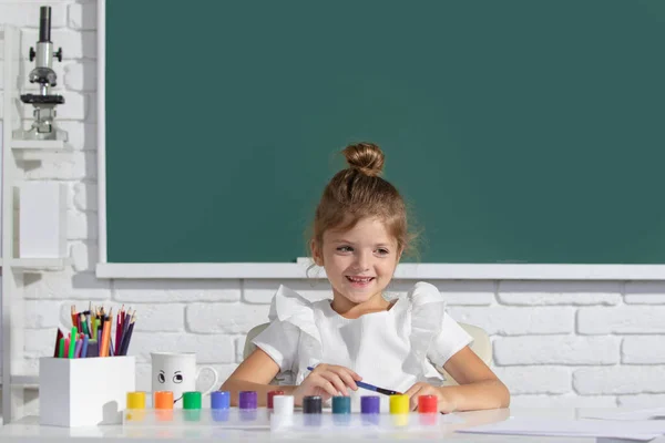 Gyermek lány rajz színező tollak festék. Aranyos kislány portréja, aki boldogan mosolyog, miközben élvezi a művészetet és a kézműves leckét az iskolában. Gyerekek korai művészet és kézművesség oktatás. — Stock Fotó