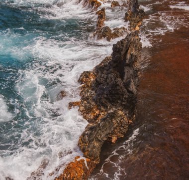 Dalgalar ve kayalık sahil manzarası.
