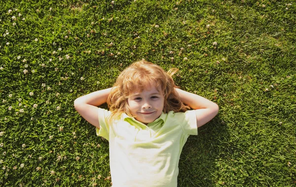 Niño caucásico acostado en la hierba. Niños disfrutando del verano. — Foto de Stock