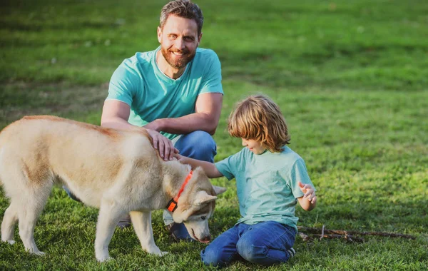 Pai e filho com cão de estimação relaxante na natureza no parque. — Fotografia de Stock
