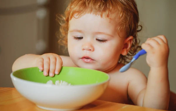 Engraçado bebê na cozinha comendo com os dedos de prato. — Fotografia de Stock