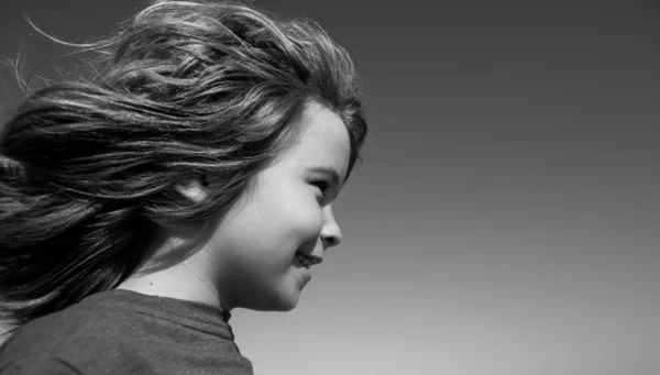 Primer plano retrato de un niño pequeño y lindo mirando hacia otro lado en el cielo azul con espacio de copia. Concepto de infancia y crianza. —  Fotos de Stock