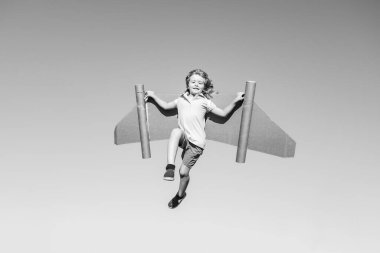 Mavi gökyüzüne karşı kağıt kanatlı mutlu çocuk. Oyuncak sırt roketli çocuk yeşil baharda dışarıda eğleniyor. Özgürlük tasasız ve çocukların hayal gücü kavramı.