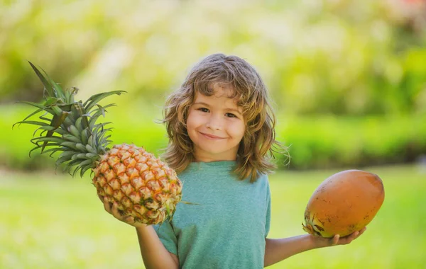 Çocuk elinde ananas ve hindistan cevizi tutarak gülümsüyor. Yaz meyveleri. — Stok fotoğraf