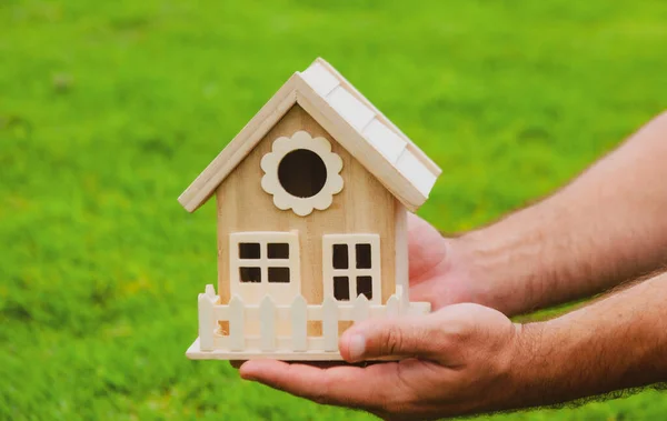 Mano masculina sosteniendo el modelo de casa de cerca. Pequeña casa de juguete en miniatura. Hipoteca propiedad sueño mudanza casa y concepto de bienes raíces. — Foto de Stock