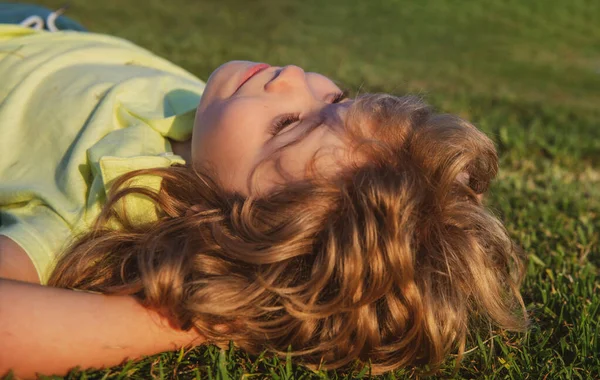 Portréty šťastných dětí hrajících a ležících na trávě venku v letním parku. — Stock fotografie