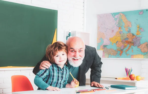 Scuola elementare. Allievo intelligente o scolaro con insegnante senior. Nonno e figlio si divertono insieme . — Foto Stock
