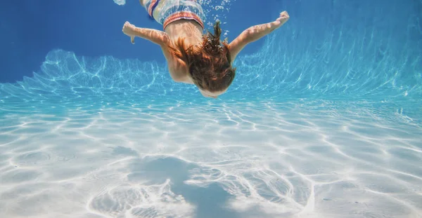 A kisfiú úszik a víz alatt. Nyaralás gyerekekkel egy trópusi üdülőhelyen. Gyerek fiú a víz alatt. — Stock Fotó