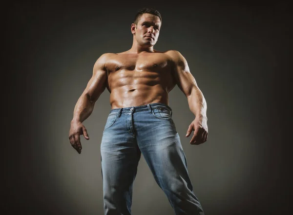 Sexy muscolare forte faccia ragazzo in jeans su grigio isolato sfondo. — Foto Stock