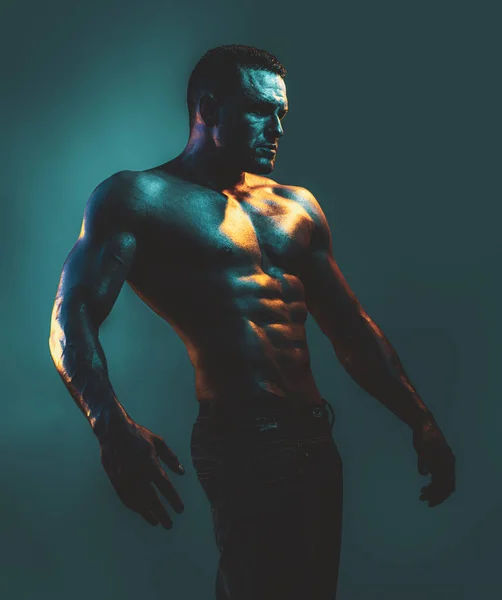 Athlète nu avec un corps fort. Un torse. Portrait d'un homme torse nu musclé sexy posant sur fond bleu néon . — Photo