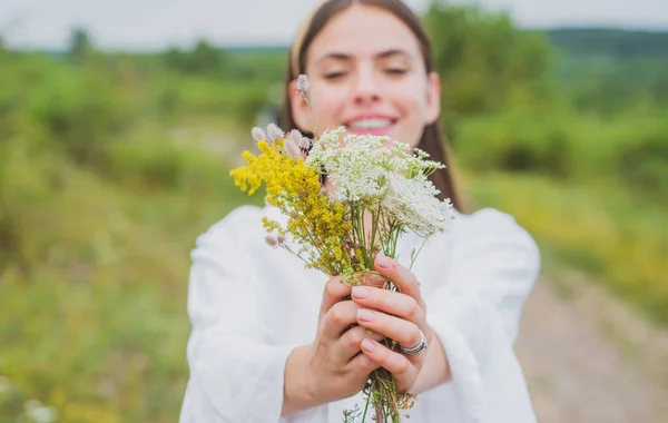 Chica sonriente de primavera en el campo. Estilo de vida saludable. Mujer en el prado con flores silvestres. Ámbito ecológico. — Foto de Stock