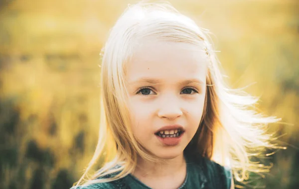 Portret van een schattig blond meisje. Portret van een engelachtig kind in zonnig daglicht. Klein Europees meisje met blond haar op zoek aantrekkelijk en evenwichtig tonen neutrale emoties. — Stockfoto