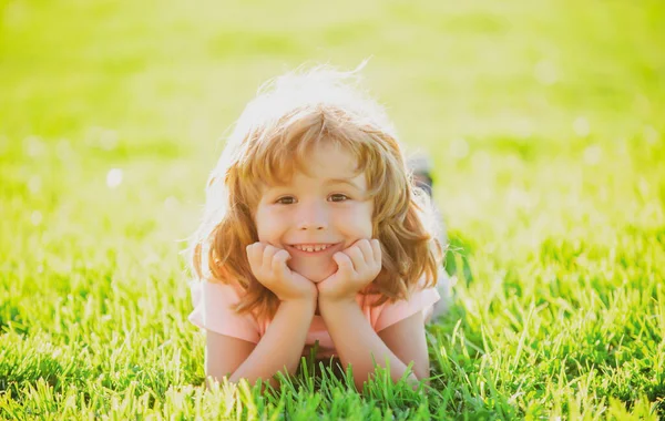 Kind im Park. Kind im Freien. Spring Boy im Gras liegend. Sommerspaziergang. Anpassung der Kinder. — Stockfoto