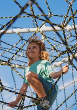 Sevimli çocuk gülümsüyor, oyun alanında oynarken mutlu..