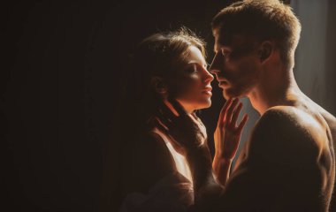 Birbirine aşık romantik bir çift siyah arka planda sarılıp öpüşüyor. Karanlık arka planda gece lambalarıyla poz veren güzel bir çift..