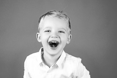 Komik çocuk suratı. Çocuk şaşkınlık ve mutluluğu ifade ediyor. Kırmızıda izole edilmiş mavi gözlü, gülümseyen çocuk portresi..