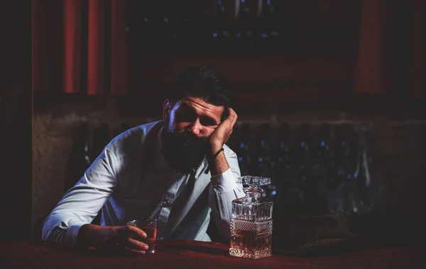 Пьяный мужчина сидит за стойкой в пабе или баре и пьет коньяк или виски. Скотч и коньяк. — стоковое фото