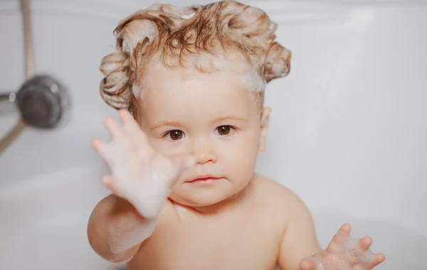 Παιδί στο ντους. Αστείο παιδί λούζεται με αφρό και πλένεται στην μπανιέρα στο σπίτι. Παιδί στην μπανιέρα με αφράτη σαπουνόφουσκα. — Φωτογραφία Αρχείου