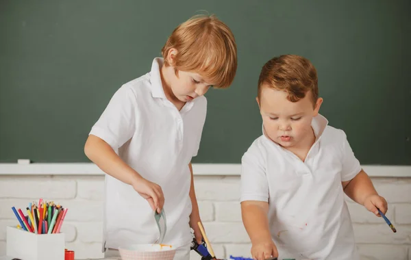 Children boys pupils drawing with coloring pens, painting with early development paints. Childhood learning, kids artistics skills. — Stok fotoğraf