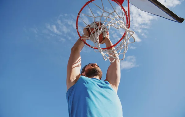 Basketbalspeler maakt een sprongschot tegen blauwe lucht achtergrond. — Stockfoto