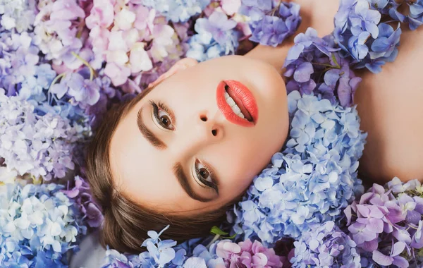 Női szépség. Egy lány, aki virágokon fekszik. Egység a természettel. Virágzik. Smink kozmetikumok és bőrápolók. — Stock Fotó