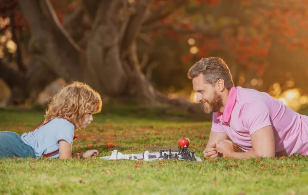 Šťastná rodina venku. Hry a zábava pro děti. Otec a syn hrají šachy v letní zahradě. — Stock fotografie