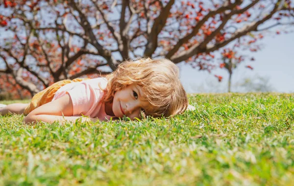 Caucasian child portrait. Kid laying in grass. — стоковое фото