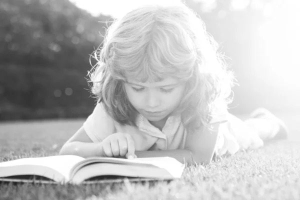 Liten pojke läser en bok i sommar solnedgång ljus. — Stockfoto