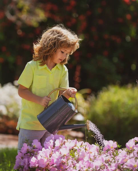 Nettes Kind, das an Sommertagen Blumen im Garten gießt. Kind mit Gießkanne an Sommertagen. Wenig Helfer. — Stockfoto