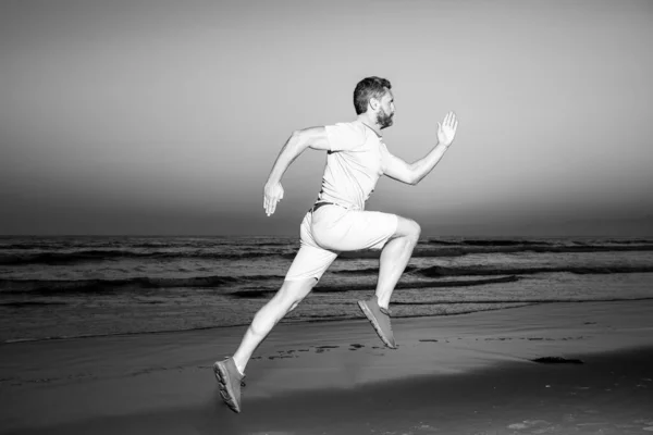 Actieve gezonde hardloper joggen buiten. Dynamische beweging. Sport en gezonde levensstijl. Fit man fitness model werken buiten door zee strand. — Stockfoto