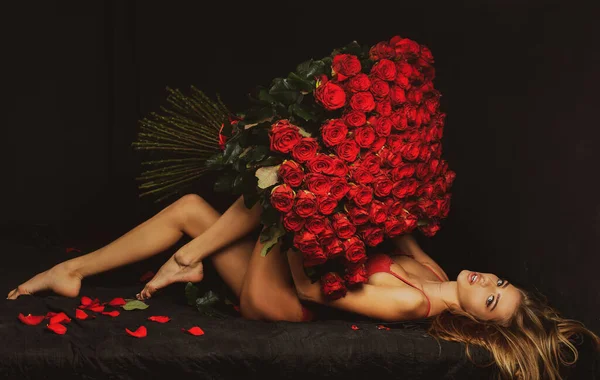 Sexy sinnliche Frau mit Rosenstrauß. Mädchen in roten Dessous mit Valentinspräsent. — Stockfoto