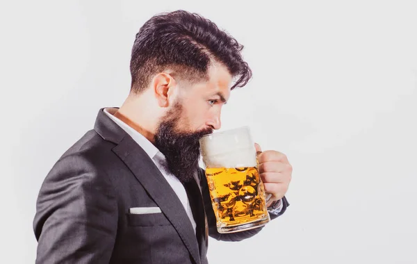 Чоловік у класичному костюмі п'є пиво. Бородатий хлопець у діловому вбранні виглядає щасливим і задоволеним. Портрет людини з піднятим високим склом пива, ізольованим на білому . — стокове фото