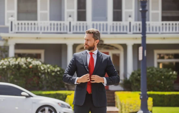 Affärsman som står utanför ett modernt hus. Fastighetskoncept. Agent redo att sälja hem. — Stockfoto