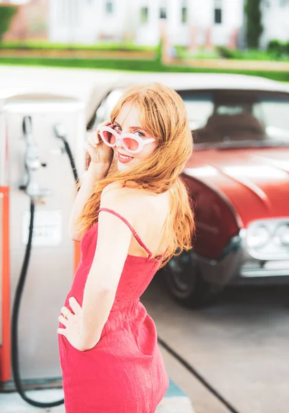 Menina sexy com vestido vermelho no posto de gasolina. — Fotografia de Stock