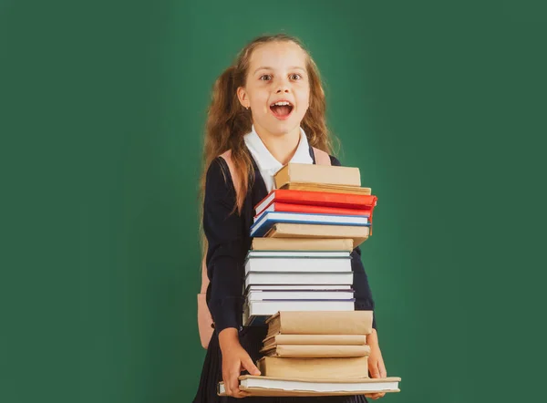 Kennisdag, lachend grappig schoolmeisje met rugzak met boeken op groen schoolbord. Een levensstijl uit de kindertijd. Onderwijs op school. — Stockfoto