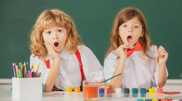 Spännande skola överraskade barn som ritade färgglada bilder med pennkritor i klassrummet. Porträtt av förvånade upphetsade elever njuter av konst och hantverk lektion. Barndomslärande, barnartistik — Stockfoto