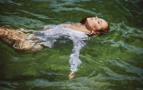 Fiatal szexi nő úszik az átlátszó, kék tengerben. Érzéki karcsú nő lebeg az óceán vizén. — Stock Fotó