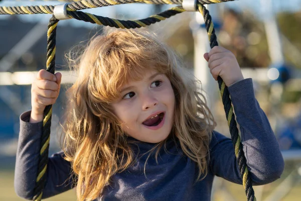 Kid boy climbing the net. Emotional portrait of a child in the playground. Outdoor kids activity. — Stockfoto